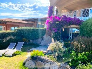 Ein Garten mit Pool, Liegestühlen und einem Gebäude mit überdachter Terrasse.