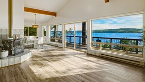 Une pièce spacieuse avec de grandes fenêtres, un ventilateur de plafond et une vue sur un lac.