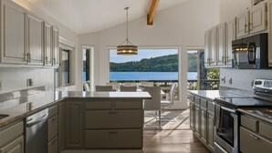 Une cuisine moderne avec vue sur un lac, dotée d’appareils électroménagers intégrés et d’un coin repas.