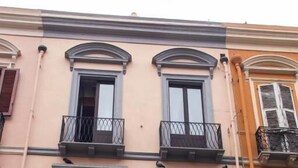 Un edificio de varios pisos con balcones, un portón de garaje y una ventana con contraventanas.
