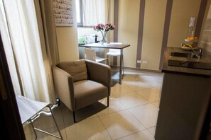 A compact living space with a kitchenette, a dining area with a table and chairs, and a small sofa.