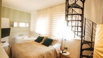 Un dormitorio con cama, mesita de noche, lámpara, televisor, ventana con persianas y una escalera.