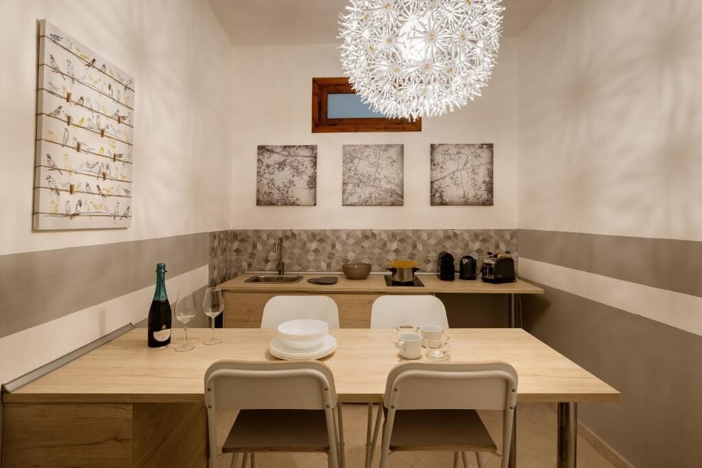 Un comedor moderno con una mesa de madera, dos sillas, una araña y obras de arte en las paredes.