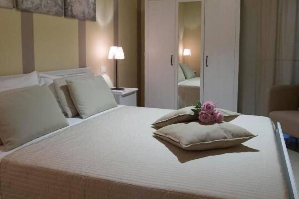 A hotel room with a bed, bedside lamps, a wardrobe, and a mirror.