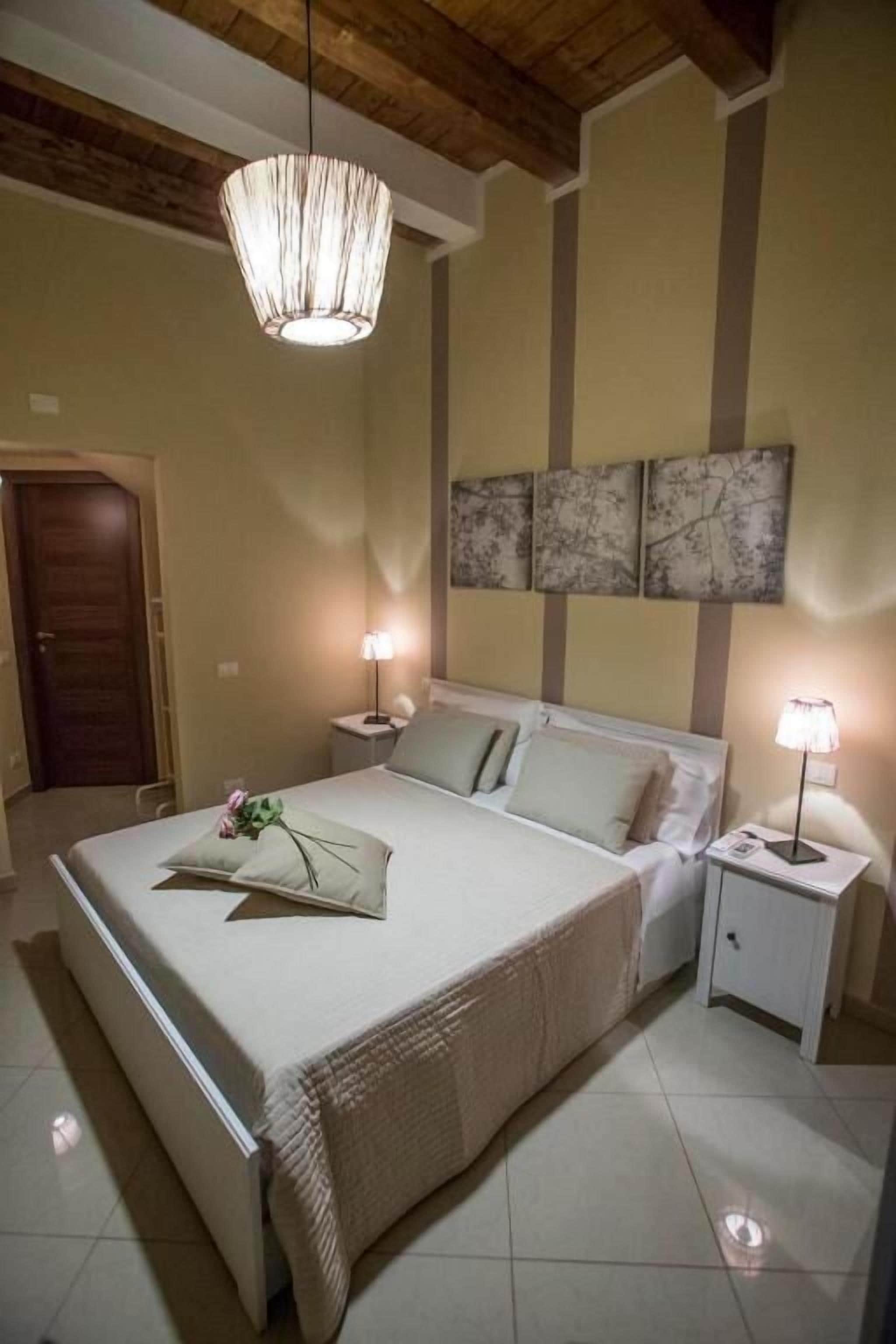 A bedroom with a bed, bedside lamps, a door, and a ceiling light fixture.