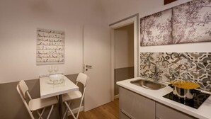 Una cocina compacta con comedor, un lavamanos y una obra de arte colgada en la pared.