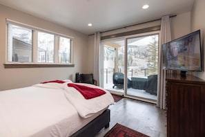 A bedroom with a large bed, a television, a sliding glass door to a balcony, and a view of a snowy landscape. - Spacious 3BR home with slope views at Purgatory, perfect for family getaways. (Durango)