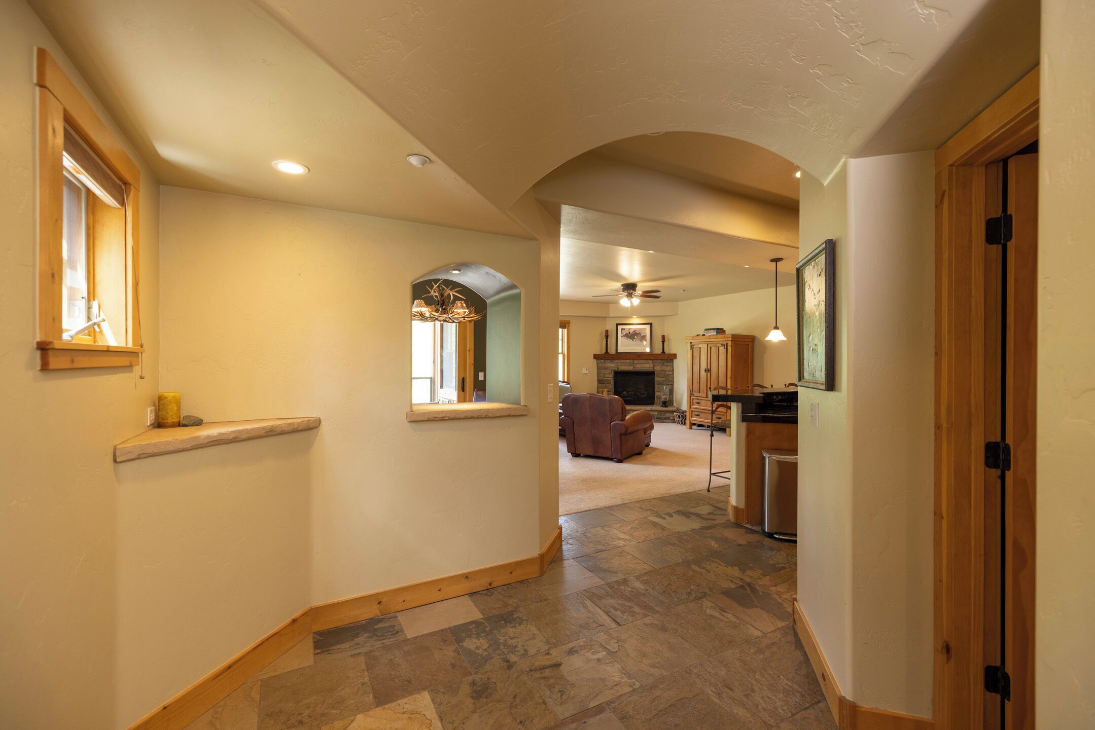 A spacious hallway with a fireplace, wooden flooring, and a view into the living area.