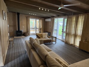 Ein gemütliches Wohnzimmer mit einer Couch, einem Tisch, einem Sessel, einem Kamin und großen Fenstern.