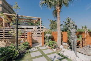 A gated entrance with a wooden gate, a palm tree, and a statue of a woman. - Glamping Trailer Lanikai (Awaji)
