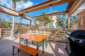 An outdoor patio with a wooden table and benches, a grill, and a pergola with a view of the surrounding area. - Glamping Trailer Lanikai (Awaji)