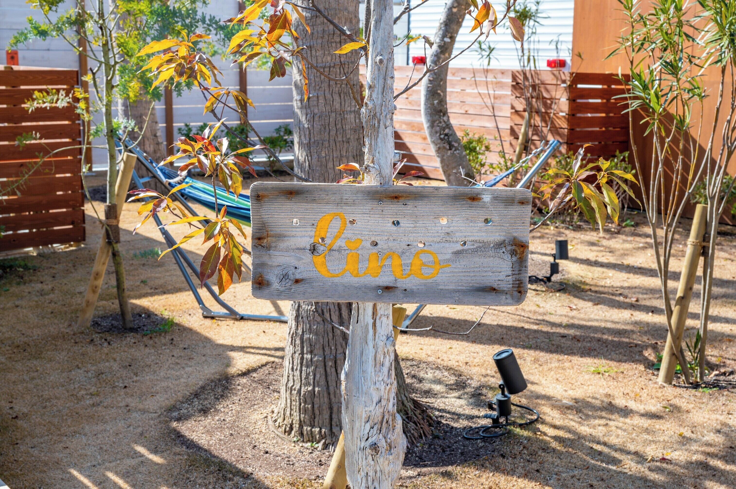 A wooden sign with the word 'Cine' painted on it, attached to a tree.