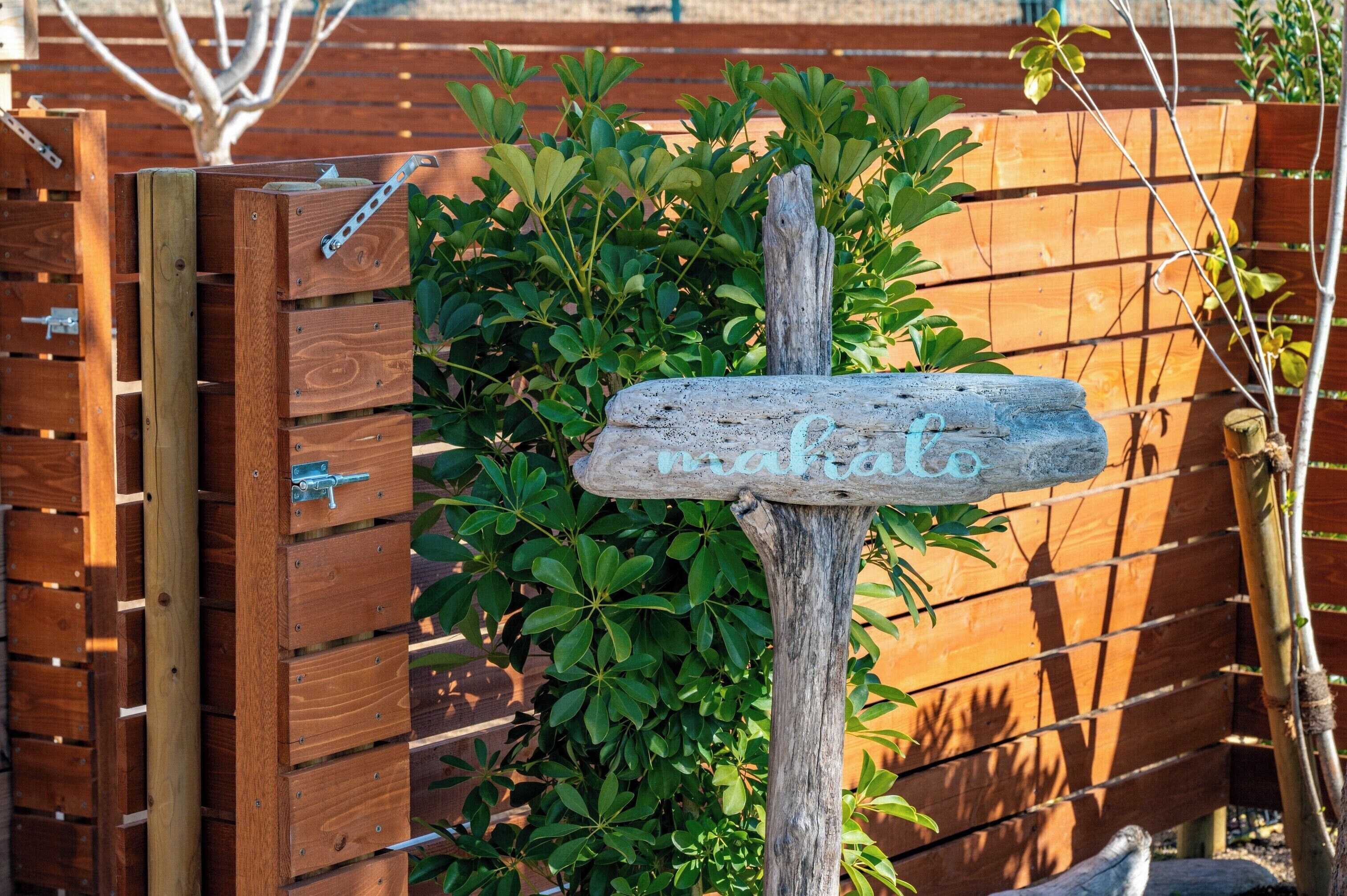 A wooden gate with a rustic signpost and greenery.