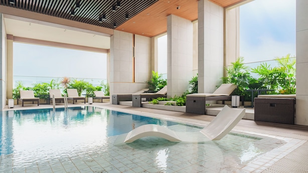 An indoor swimming pool with lounge chairs, a slide, and potted plants. - Imperial Suites by Kieu by Kita (Ho Chi Minh City)