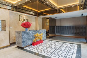 A hotel reception area with a marble reception desk, a welcome sign, a red flower vase, and a patterned floor. - Imperial Suites by Kieu by Kita (Ho Chi Minh)
