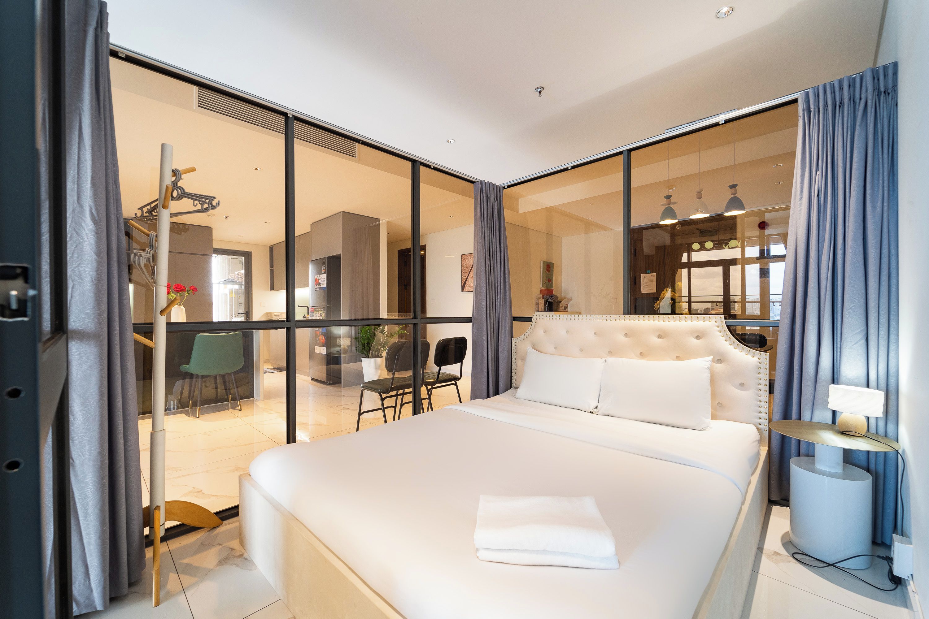 Ein modernes Hotelzimmer mit einem großen Bett, einem Schreibtisch und Blick durch eine Glastür.