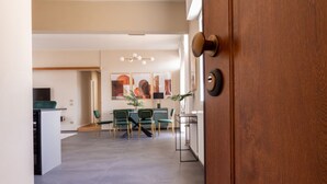 Puerta abierta a un comedor con cocina moderna, sillas verdes y una mesa de comedor.