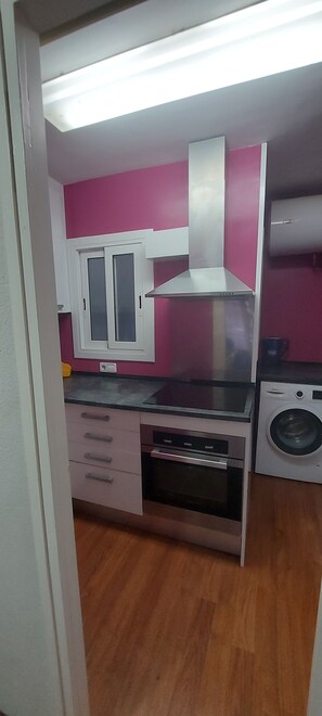 Cocina compacta equipada con microondas, horno y lavadora.