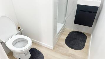 A modern bathroom with a toilet, a shower, and a sink.
