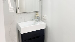 A bathroom with a white sink, a mirror, and a black cabinet. - Charming Studio Steps from City Center (Ghent)