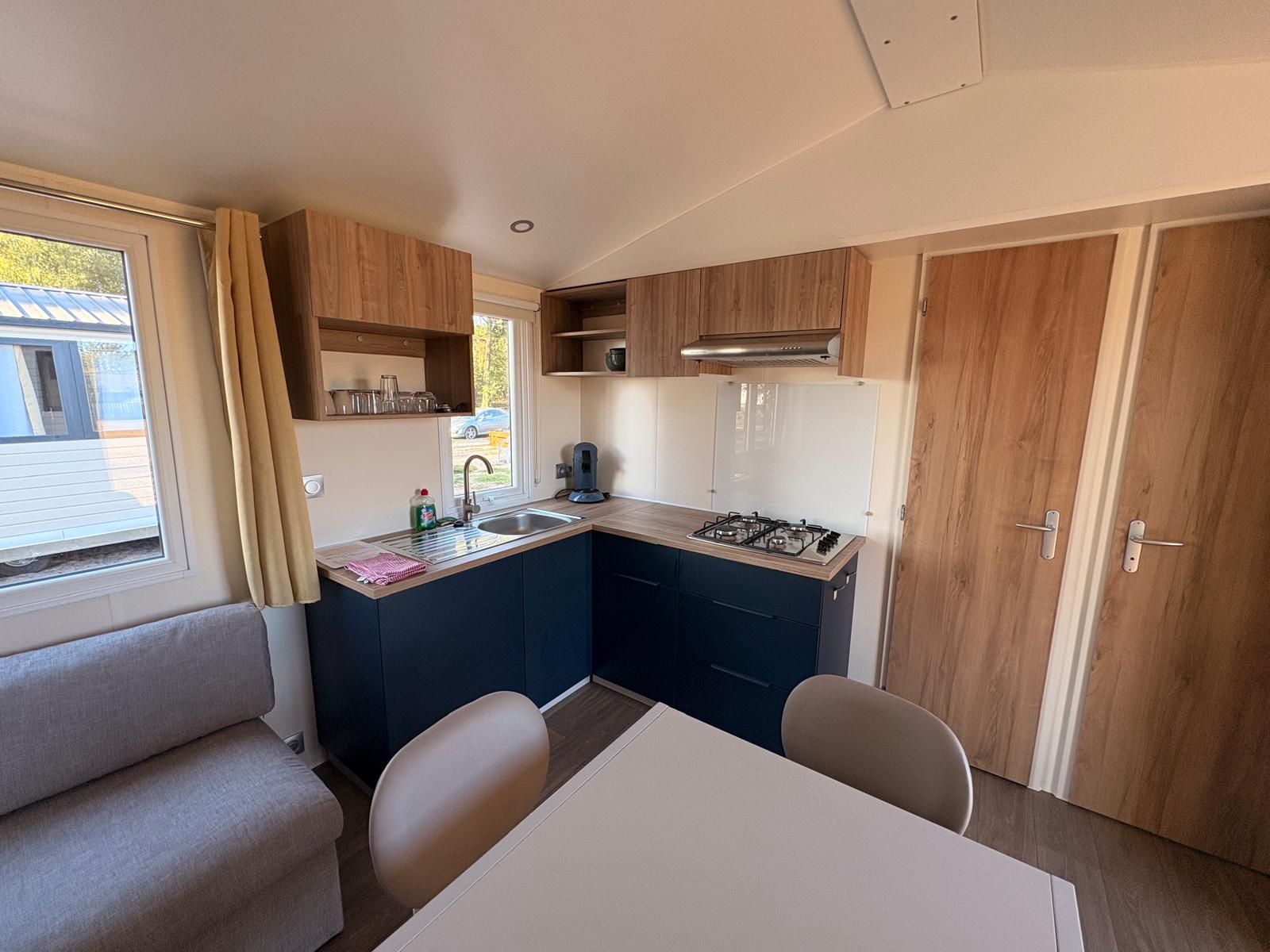 A compact kitchenette with a gas stove, sink, and wooden cabinets.