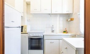 A compact kitchen with white cabinets, a built-in oven, and a sink. - Hostdomus - Gassa d'amante (Finale Ligure)