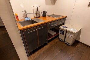 A compact kitchenette with a sink, a kettle, a coffee maker, and two waste bins labeled 'Unburnable' and 'Burnable.' - Irodori Hotel DAIDAI (Fukuoka)