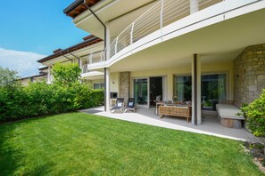 Ein modernes Haus mit überdachter Terrasse, Gartenmöbeln und einem gepflegten Rasen.