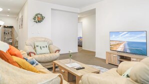 Un soggiorno con divano, tavolino, televisore e vista sulla spiaggia.