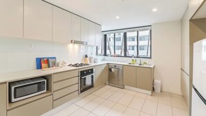 Una cucina moderna con piano cottura a gas, forno, lavastoviglie e una finestra vista edifici.