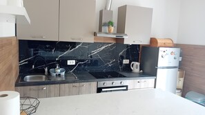 Eine moderne Küche mit schwarzem Marmor-Arbeitsplatz, Edelstahlgeräten und Holzausbau.