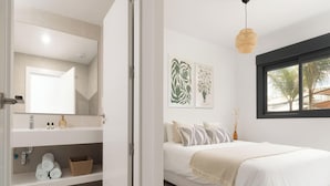 Une chambre à coucher avec un lit, une fenêtre, un miroir et des œuvres d’art accrochées au mur.
