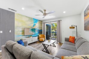 Ein modernes Wohnzimmer mit einer Couch, einem Sessel, einem Couchtisch und Kunstwerken an der Wand.