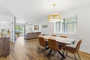 Ein moderner Essbereich mit einem Holztisch, braunen Stühlen, einer Pendelleuchte und Blick durch das Fenster.