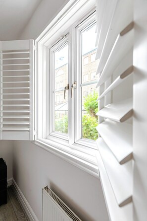 Ein Zimmer mit Fenster, Heizkörper und einer Tür mit Jalousien.