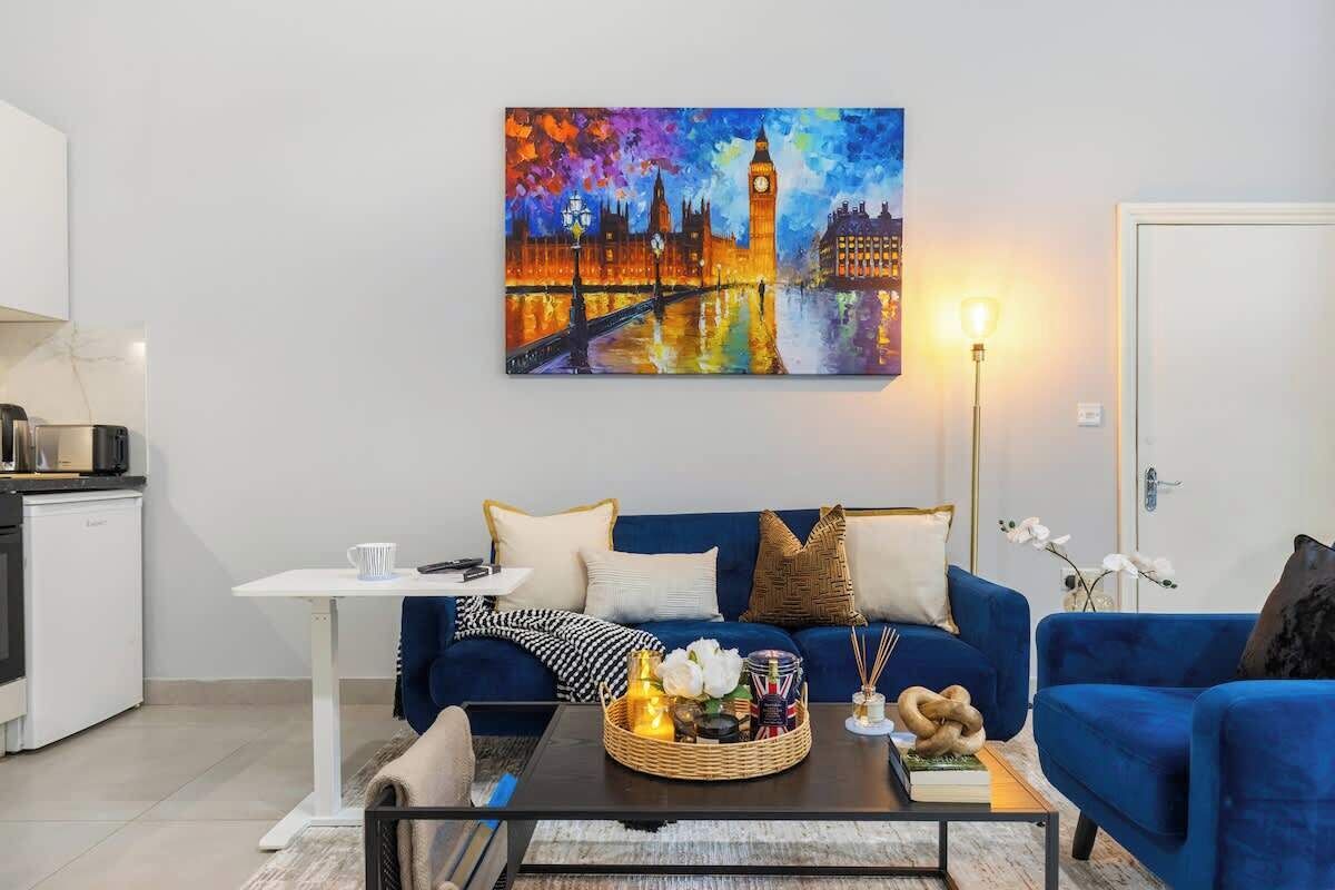 A modern living room with a blue sofa, a coffee table with a decorative basket, and a painting of a cityscape.