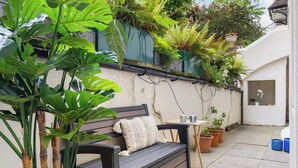 A patio with a wooden bench, potted plants, and a small table. - 1-Bed & Patio - 2 Min Walk to Abbey Road Studios (Greater London)