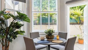 A dining area with a round table, chairs, and a potted plant. - 1-Bed & Patio - 2 Min Walk to Abbey Road Studios (Greater London)
