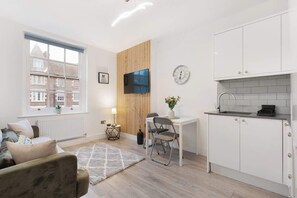 Ein modernes Apartment mit Küche, Essbereich und einem großen Fenster.
