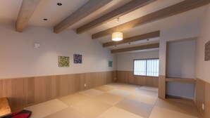 A spacious room with tatami flooring, wooden beams, a hanging light fixture, and artwork on the walls. - Irodori Hotel MOMO (fukuokashi,hakataku,katakasu)