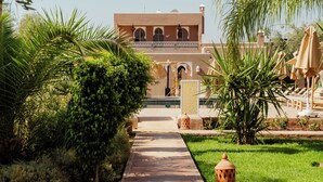 A pathway leading to a building with a balcony and a decorative column. - Les Villas du Douar (Marrakech)
