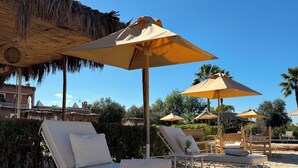 A beachside lounge area with sun loungers and thatched umbrellas. - Les Villas du Douar (Marrakech)