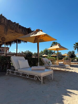 Eine Strandlounge mit Liegestühlen und Reetdachsonnenuren.