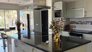 A modern kitchen with a central island, stainless steel appliances, and a large window providing natural light. - Les Villas du Douar (Marrakech)