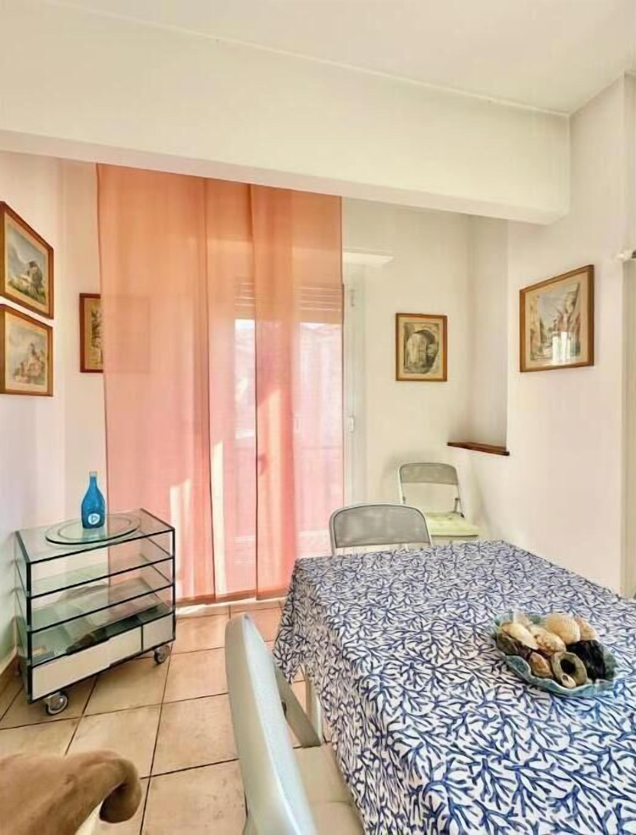 A room with a bed, a chair, a small table, and a window with curtains.