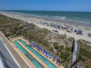 Ein Strandresort mit Poolbereich, Strandliegen und einer Promenade.