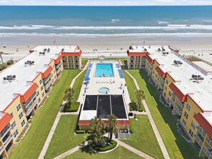 Ein Hotel mit Dachpool, mehreren Balkonen und Blick auf den Strand.