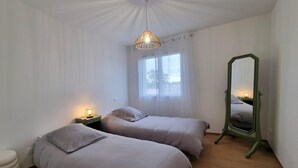 Ein Schlafzimmer mit zwei Betten, einem Fenster, einem Spiegel und einer Pendelleuchte.