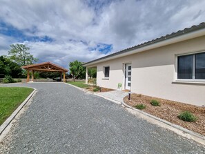 Ein Gebäude mit überdachtem Außenbereich, einem Schotterweg und einem kleinen Garten.