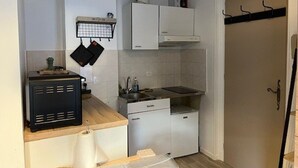 Una cocina compacta con gabinetes blancos, estufa, lavaplatos y una pequeña encimera.